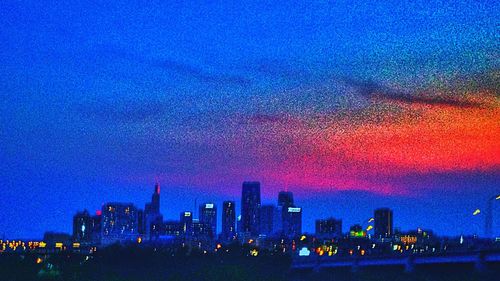 Illuminated cityscape against cloudy sky