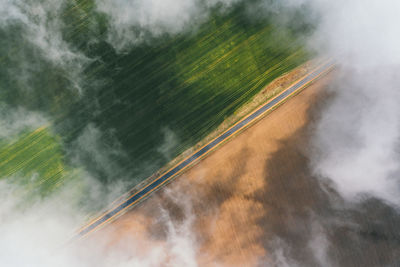Aerial view of green farmland fields through white clouds. shadows on the ground