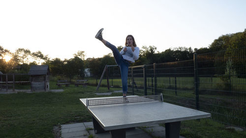 Woman sitting on bench against clear sky