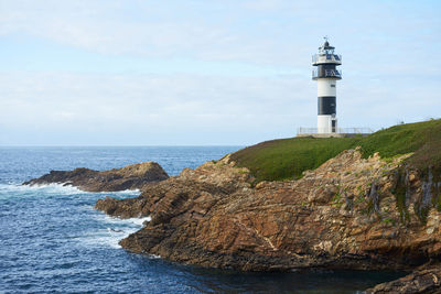 Lighthouse by sea against sky