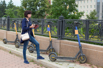 An adult woman is renting an electric scooter first time through a phone app.