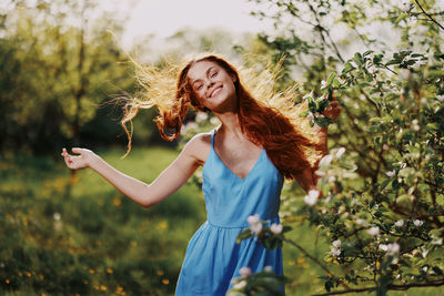 Portrait of young woman standing against plants