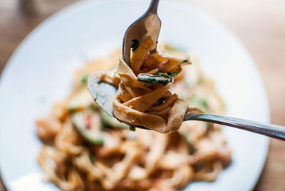 Close-up of spoon and fork with tagliatelle pasta over plate