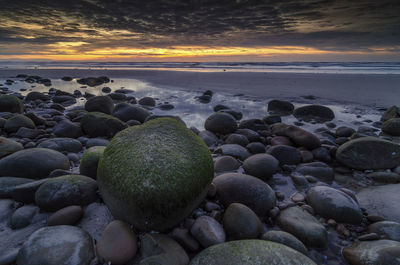 Pebbles on beach at sunset