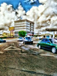 Cars parked on street against cloudy sky