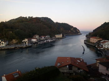 Boats sailing in river by city against clear sky