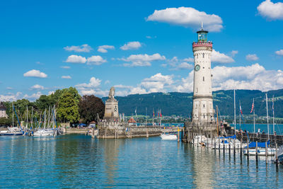 View of lighthouse by buildings against sky