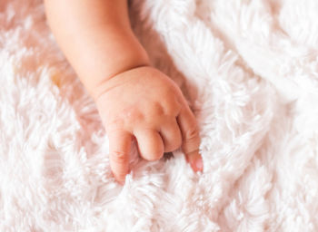 High angle view of baby hand on bed