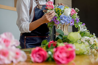 Midsection of woman arranging flowers in bouquet 