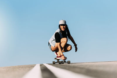 Woman skateboarding against blue sky