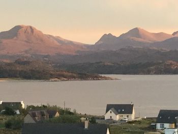 Houses by river and mountains against sky