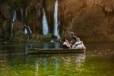 People enjoying in water happy family on a boat near waterfalls