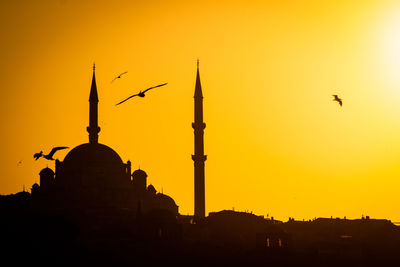 Silhouette birds flying against sky during sunset