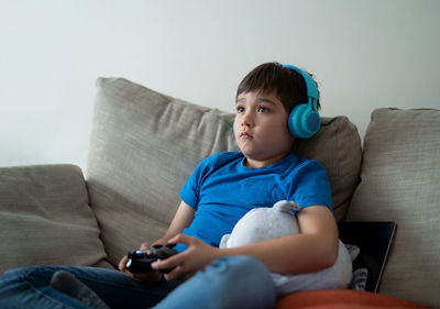 Boy using phone while sitting on sofa at home