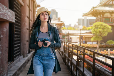 Portrait of woman standing against railing in city