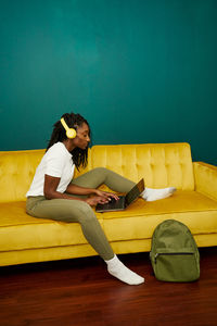 Black styled student sitting on a sofa with a computer