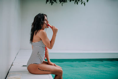 Woman sitting in swimming pool against sea