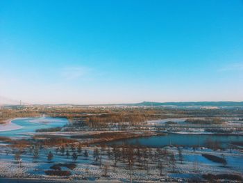 Scenic view of landscape against clear blue sky during winter