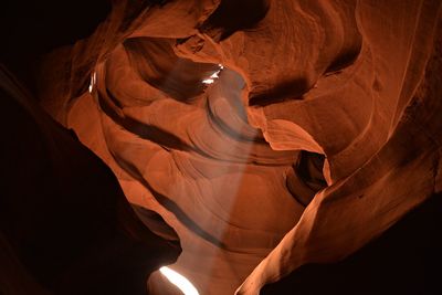 Low angle view of sunbeam streaming from rock formation in antelope canyon