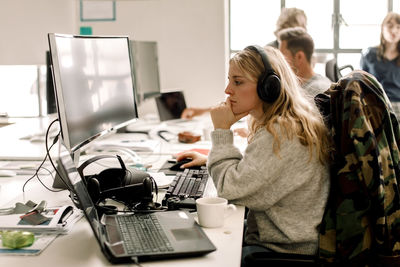 Female colleague looking at computer while working in office