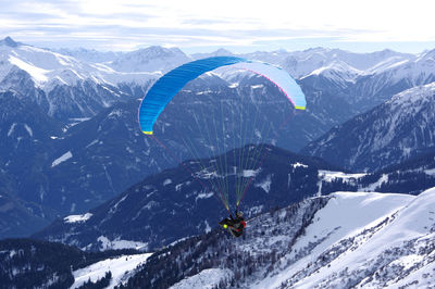 Man paragliding over snowcapped mountains