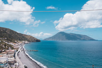 Scenic view of sea by mountains against sky