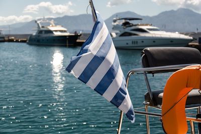 Greek flag on sailboats moored on sea against sky