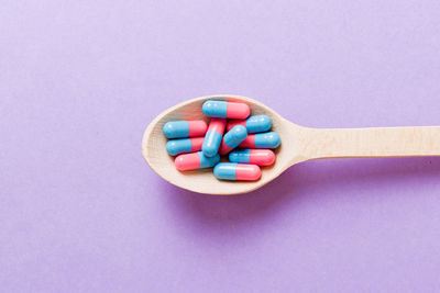 High angle view of pills in spoon against blue background