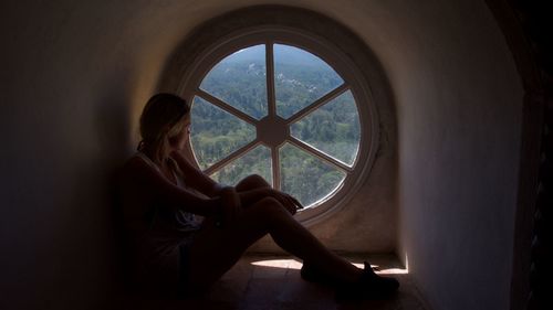 Full length of young woman sitting by window