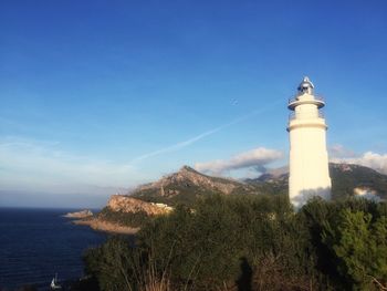 Lighthouse by sea against sky