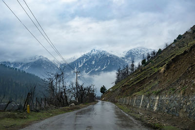 Road amidst snowcapped mountains against sky