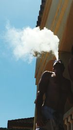 Low angle view of shirtless man standing against sky