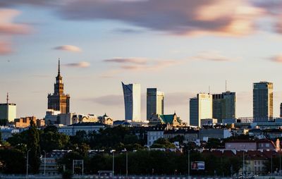 Palace of culture and science by buildings in city against sky