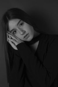 Portrait of young woman against black background