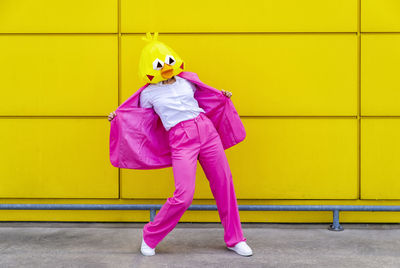 Full length of woman standing against yellow wall