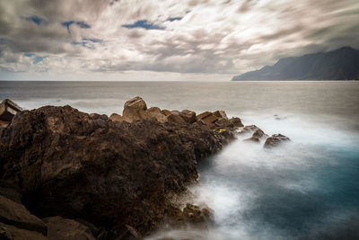 Rocks on sea shore against sky