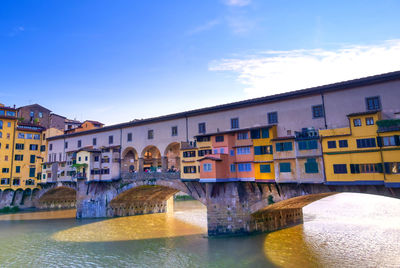 Arch bridge over river against buildings in city