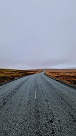 Road amidst field against clear sky