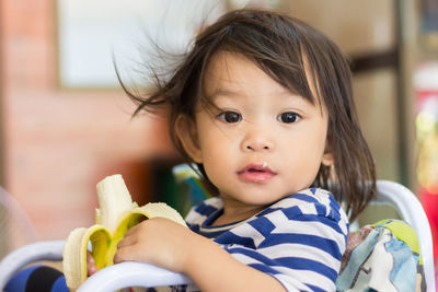 Portrait of cute baby girl eating banana