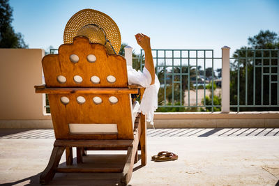 Man sitting on chair against sky