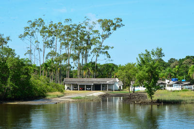 House by lake and trees against sky