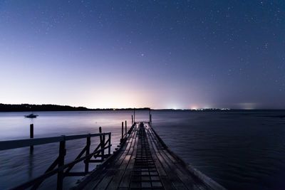 View of jetty in calm sea at night