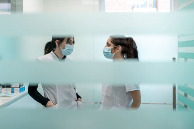 Nurses in protective face masks discussing at maxillofacial clinic