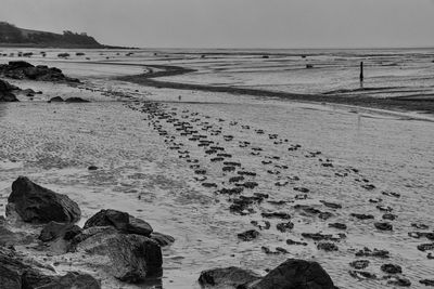 Scenic view of footprints on beach against sky 