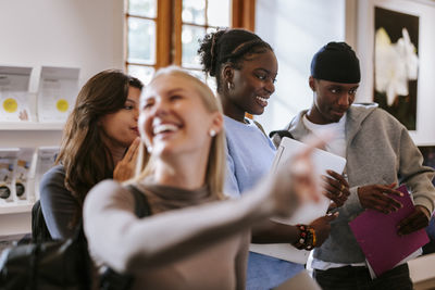 Side view of friends using digital tablet while standing at home