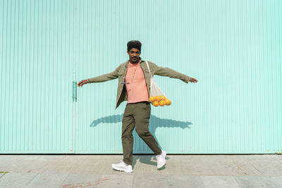 Full length of young man standing against wall