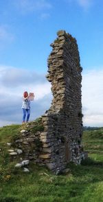 Full length of man standing by stone wall against sky