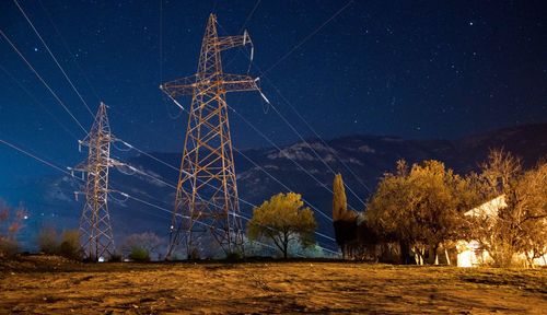 Low angle view of electricity pylon against sky at night