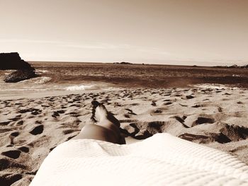 Low section of woman relaxing on sand at beach