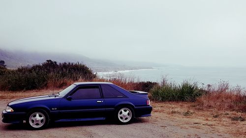 Vintage car on beach against sky